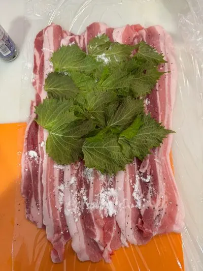 ラップの上に並べた豚バラ肉と大葉
